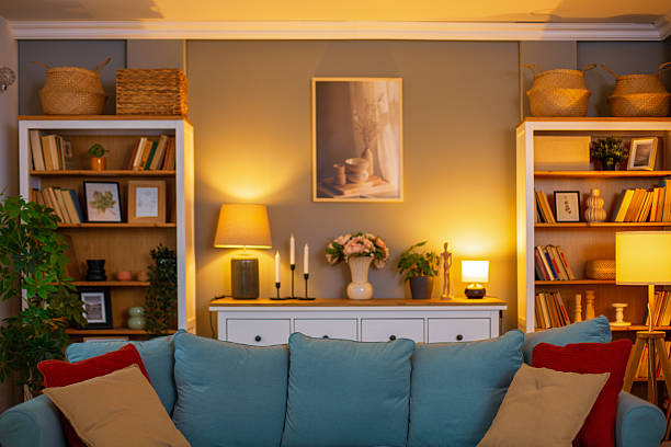 Small cozy living room with soft yellow lighting, wall-mounted reading lamps, and corner floor lamp